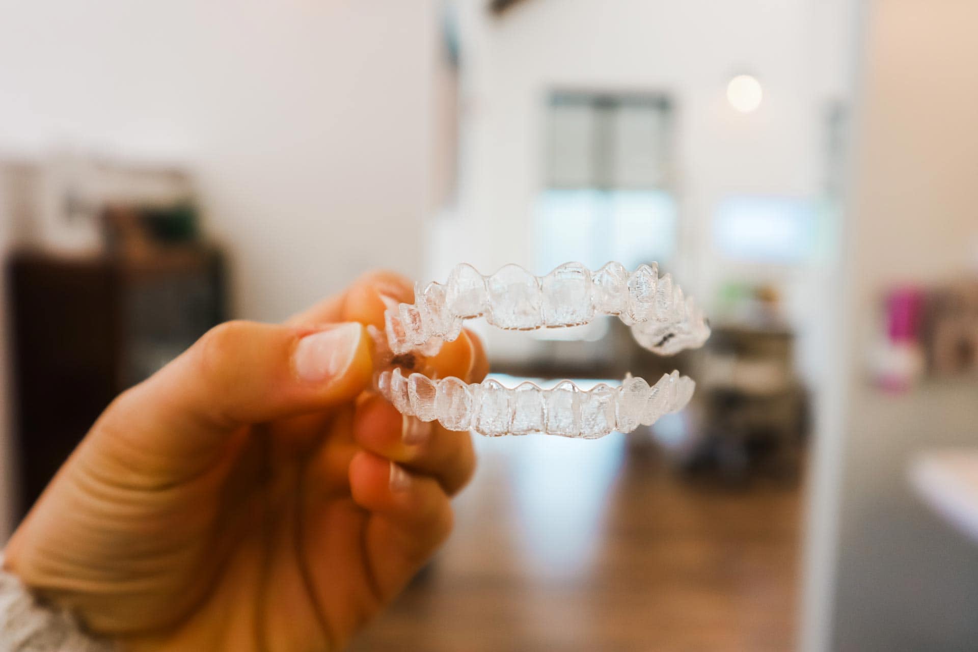 A nurse holding clear aligners in a modern office.