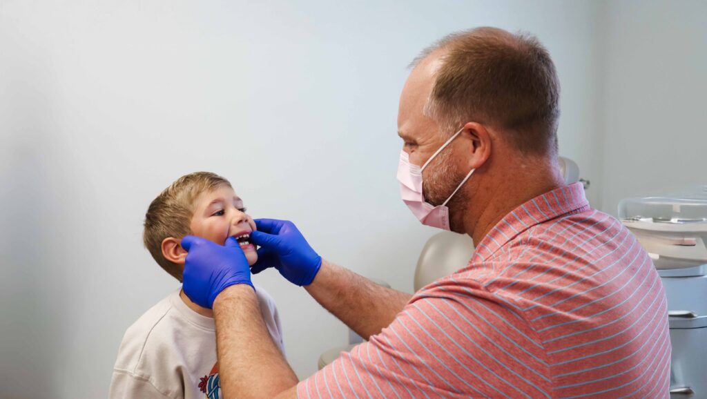 Orthodontist Dr. Rush Baker examining the bite of a young patient