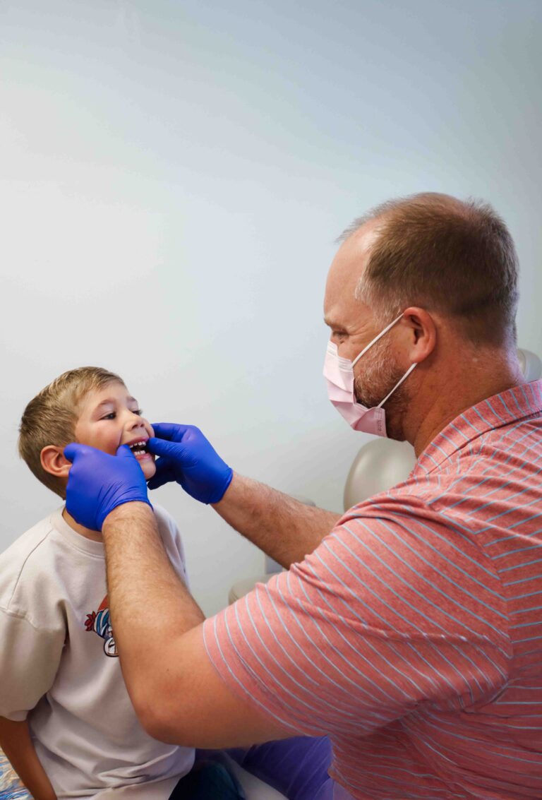 South Carolina Orthodontist Dr. Baker examining the bite of a young patient with latex gloves