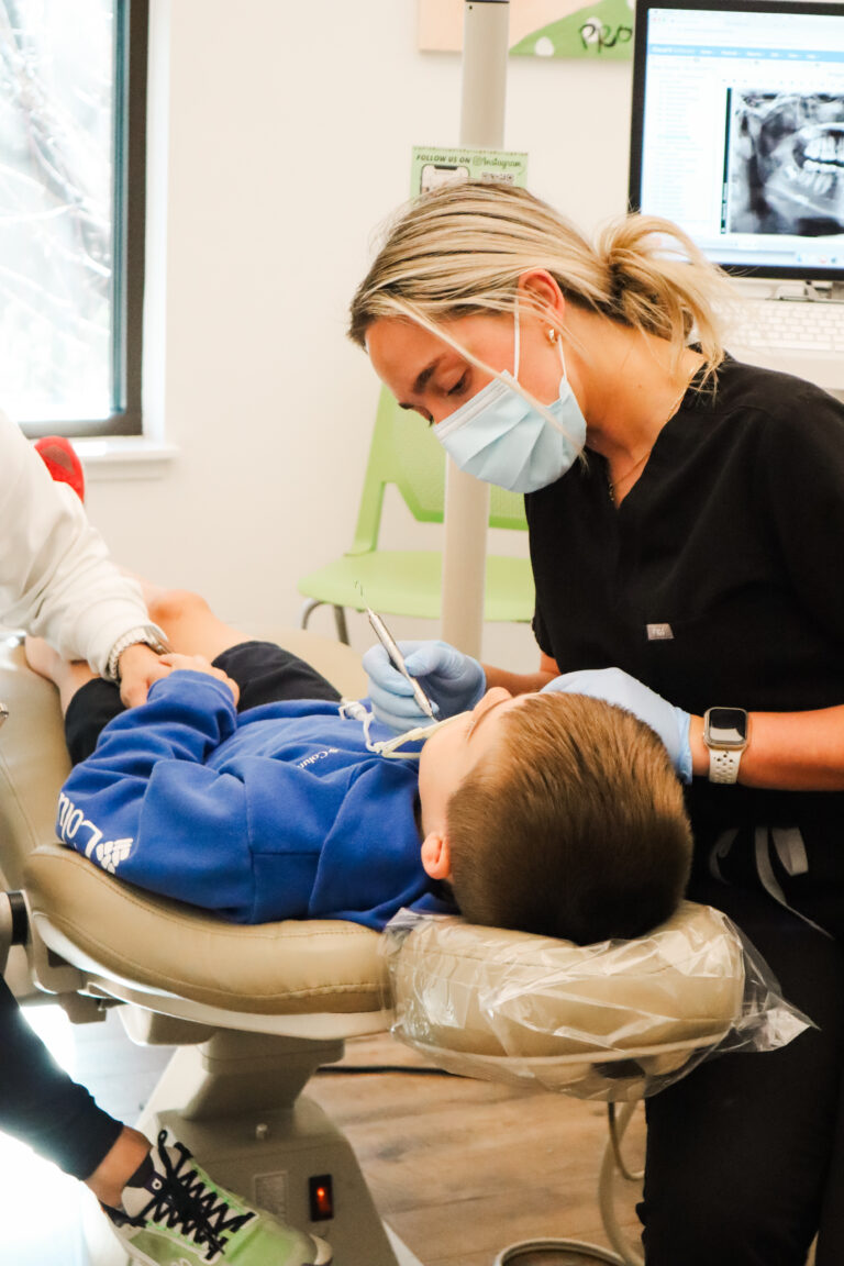 Young child having his braces maintenance by his orthodontist while his parent holds his hand