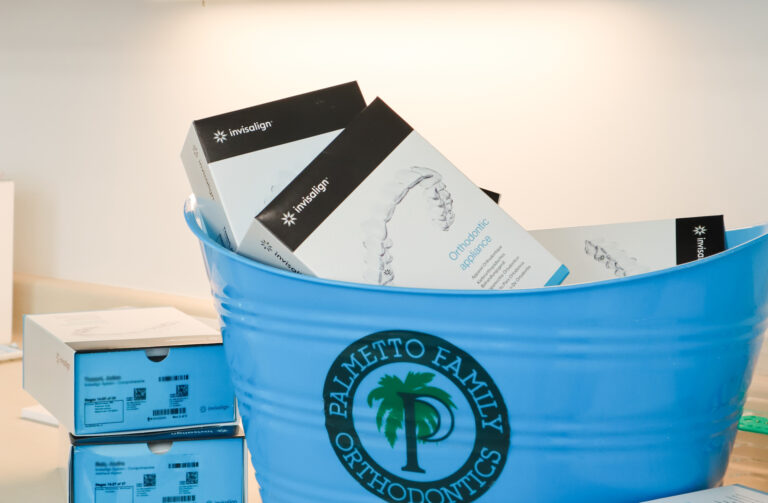 Boxes of Invisalign® clear aligners in a blue Palmetto Family Orthodontics bucket