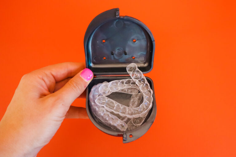 Person holding a black tray filled with 4 clear aligners